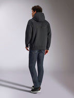 Alpinestars Emergent Oversized Hoodie, Black, back view showing 3D embroidered Alpinestars word logo across the shoulders, oversized fit, styled with dark blue denim jeans and black sneakers, casual motorsport-inspired streetwear.