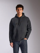 Alpinestars Emergent Oversized hættetrøje, sort, mandlig model iført oversized pullover fleece-hættetrøje, tonalt 3D-broderet Astars-logo, kængurulomme, hætte med snøre, casual motorsport-inspireret streetwear
