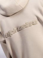 Alpinestars Emergent Oversized Hoodie, afslappet streetwear, sand, detaljevisning af tonalt 3D-broderet Alpinestars-ordlogo på ryggen, premium fleece-tekstur