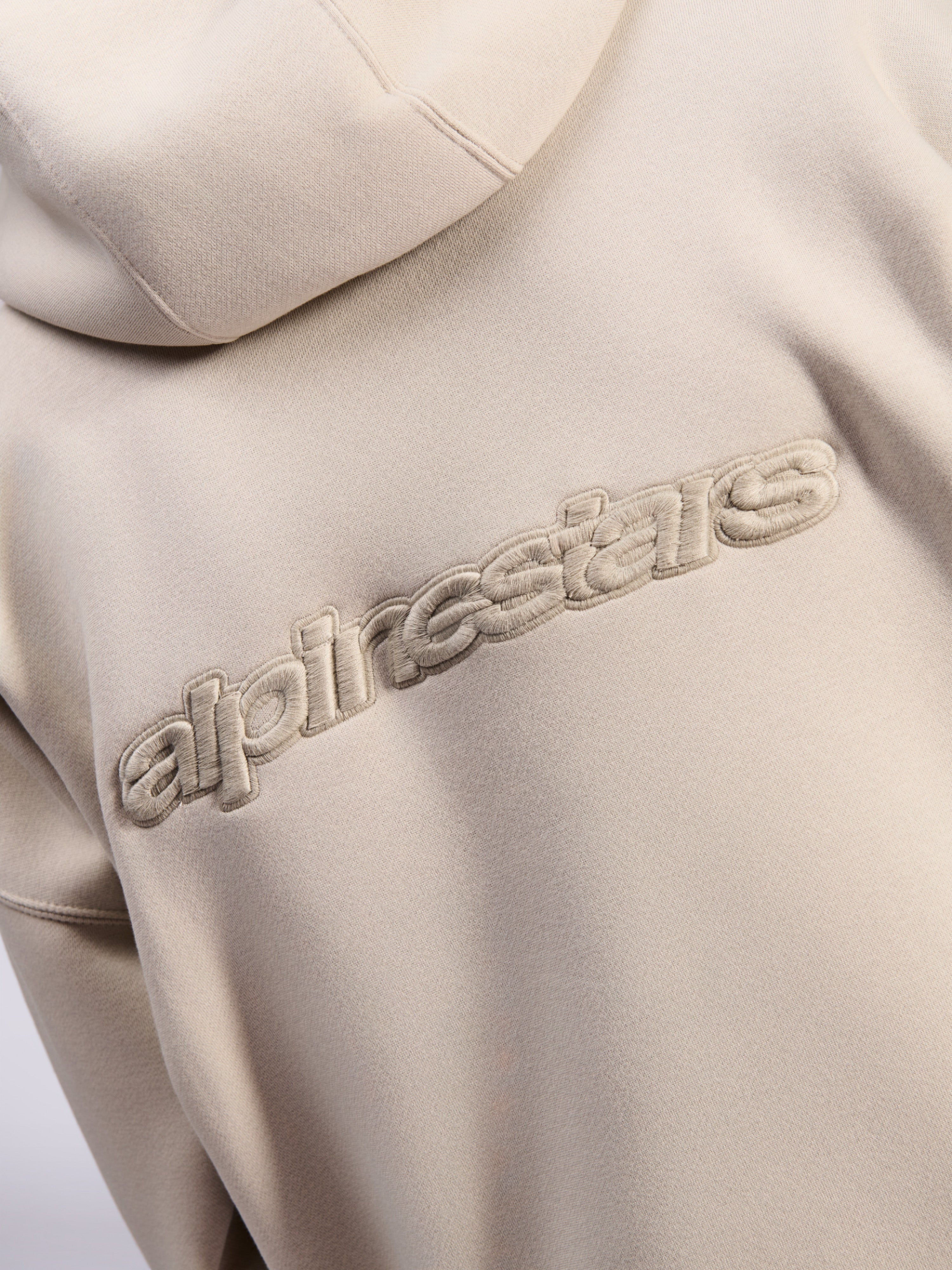 Alpinestars Emergent Oversized Hoodie, afslappet streetwear, sand, detaljevisning af tonalt 3D-broderet Alpinestars-ordlogo på ryggen, premium fleece-tekstur