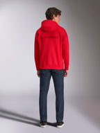 Alpinestars Emergent Oversized Hoodie, rød, set bagfra på mandlig model, med tone-i-tone 3D-broderet Alpinestars ordlogo, båret med mørkeblå jeans, afslappet motorsport-inspireret streetwear