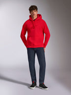 Alpinestars Emergent Oversized Hættetrøje, rød, med tonalt 3D-broderet Astars-logo på brystet, kængurulomme og hætte med snøre, båret af en model med mørkeblå jeans og sorte sneakers, afslappet lifestyle streetwear