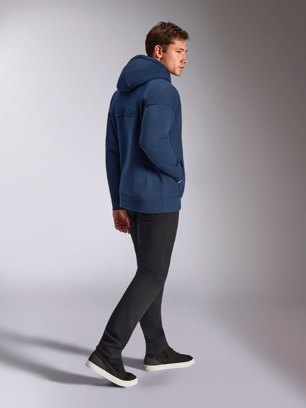Alpinestars Emergent Oversized Hættetrøje i marineblå, set bagfra med 3D-broderet Alpinestars-tekstlogo, oversized fleece-pasform med hætte med snoretræk, båret med sorte bukser, afslappet motorsport-inspireret streetwear