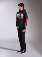 Alpinestars Obsessed hættetrøje, sort pullover-fleece, med en stor hvid plettet grafik på brystet, et rødt Astars-logo og rød branding på ærmerne, båret af en model med sorte bukser og sneakers, afslappet motorsport-streetwear