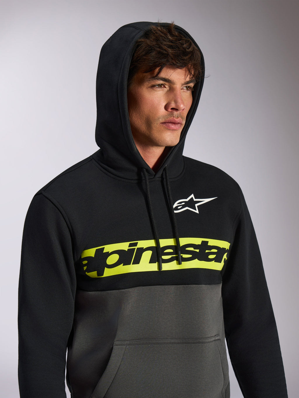 Alpinestars Parallel hættetrøje, afslappet streetwear med farveblokering, sort overdel og gunmetal grå underdel, neongult brystbånd med sort Alpinestars ordlogo, hvidt Astars-logo, pullover med hætte og snøre