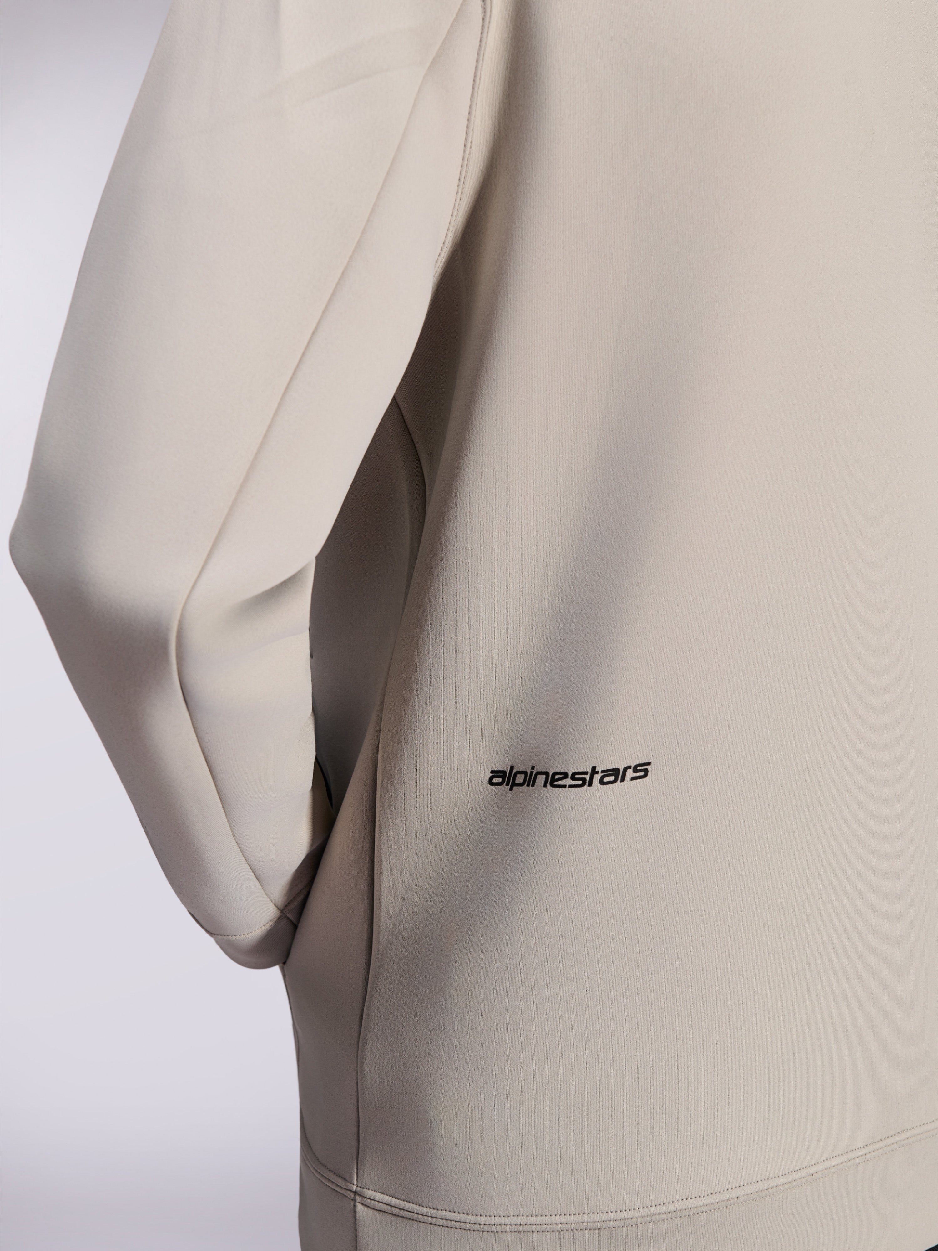 Alpinestars Cypher Hoodie, hættetrøje med lynlås i dobbeltsidet fleece, Cementgrå, nærbillede af lille sort Alpinestars-ordlogo nederst på ryggen, detalje af lomme i sømmen og glat tekstur i stoffet