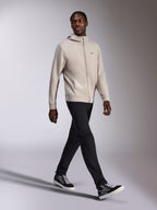 Alpinestars Cypher Hoodie, cementgrå fleece med gennemgående lynlås, højhalset hætte, lille Astars-logo på brystet, båret af en gående model, kombineret med sorte bukser og sort-grå sneakers, afslappet motorsport-inspireret sportstøj