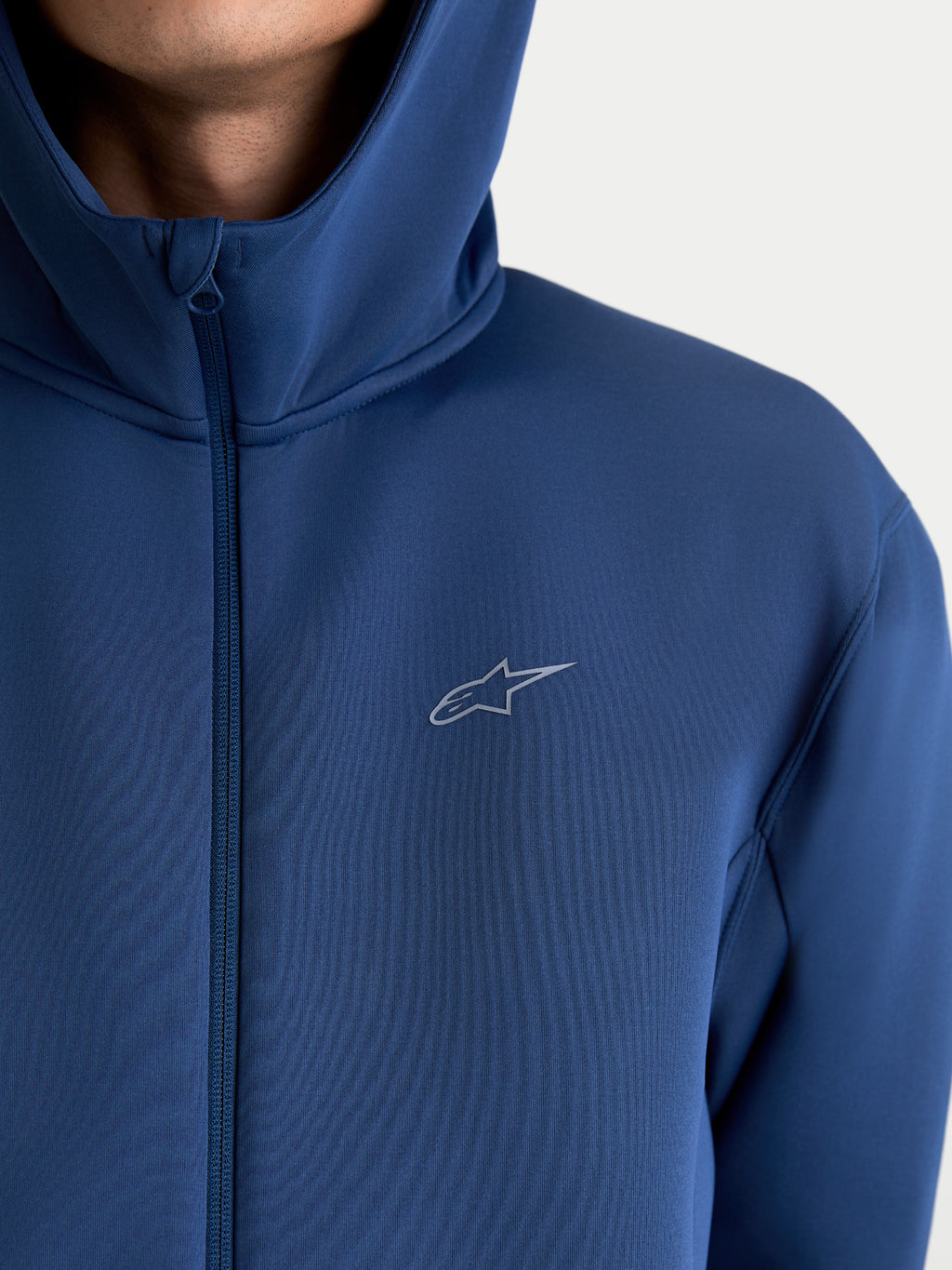 Alpinestars Cypher hættetrøje, sportswear hættetrøje med lynlås til herre og dame, blå og grå, teknisk tri-blend fleece-stof med højhalset hætte og lille Astars-logo, nærbillede på model.