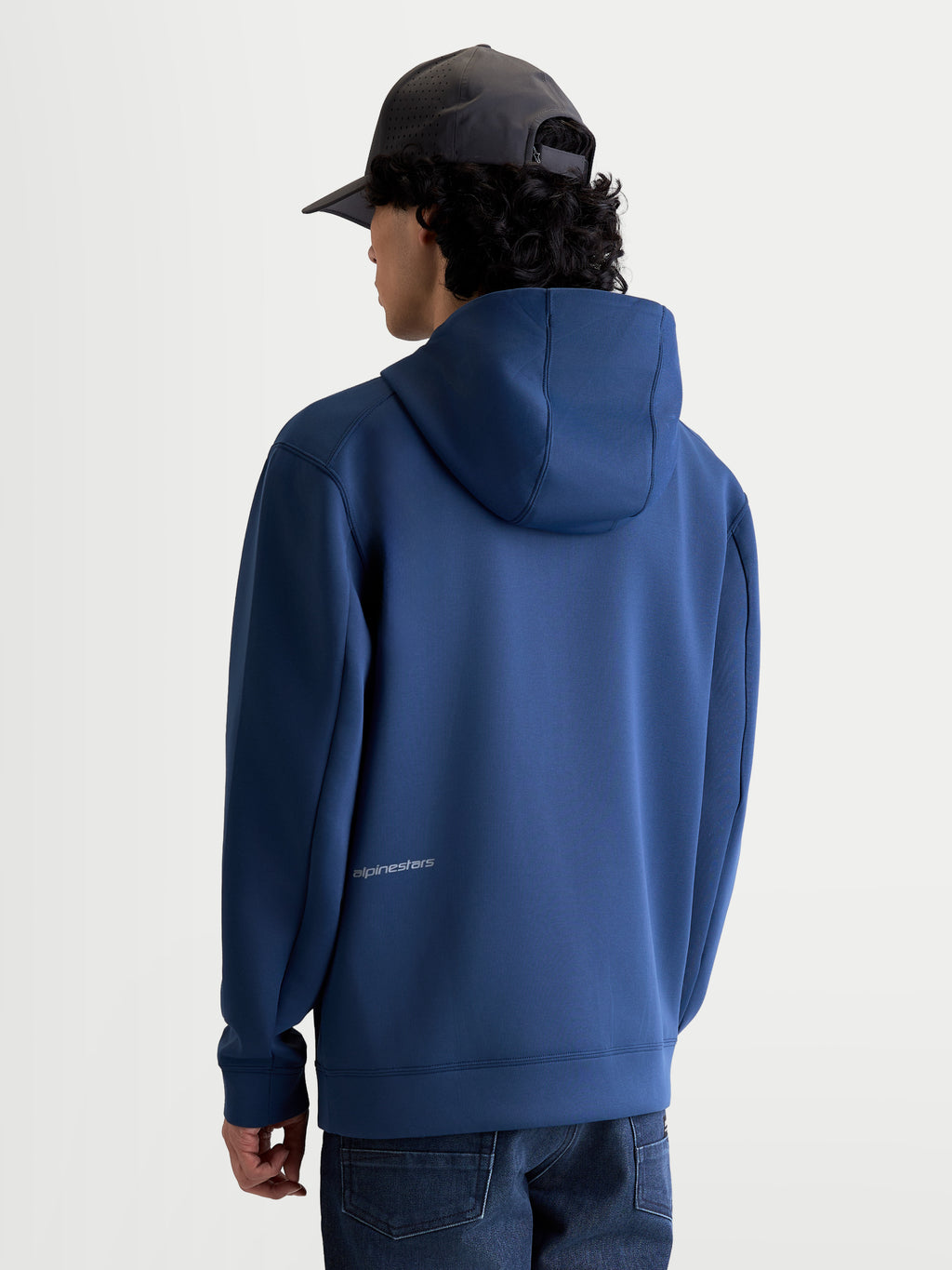 Alpinestars Cypher hættetrøje, blå sportswear-fleece set bagfra på model med højhalset mesh-foret hætte og diskret Alpinestars-logo nederst på ryggen, førsteklasses tri-blend materiale til afslappet motorsport-stil.