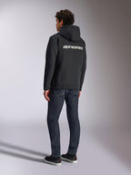 Alpinestars Transverse Hoodie, sort fleecehættetrøje med lynlås, set bagfra med hvidt Alpinestars-tekstlogo over skuldrene, båret med mørkeblå jeans og sorte sneakers, afslappet motorsport-inspireret streetwear