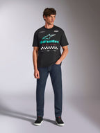 Alpinestars Aplomb Oversized CSF Tee, kortærmet t-shirt, sort, Astars-logo med blågrøn farveovergang, rød 'Racing Ahead'-tekst og ternede detaljer, båret af model med mørkeblå jeans, afslappet motorsport-streetwear