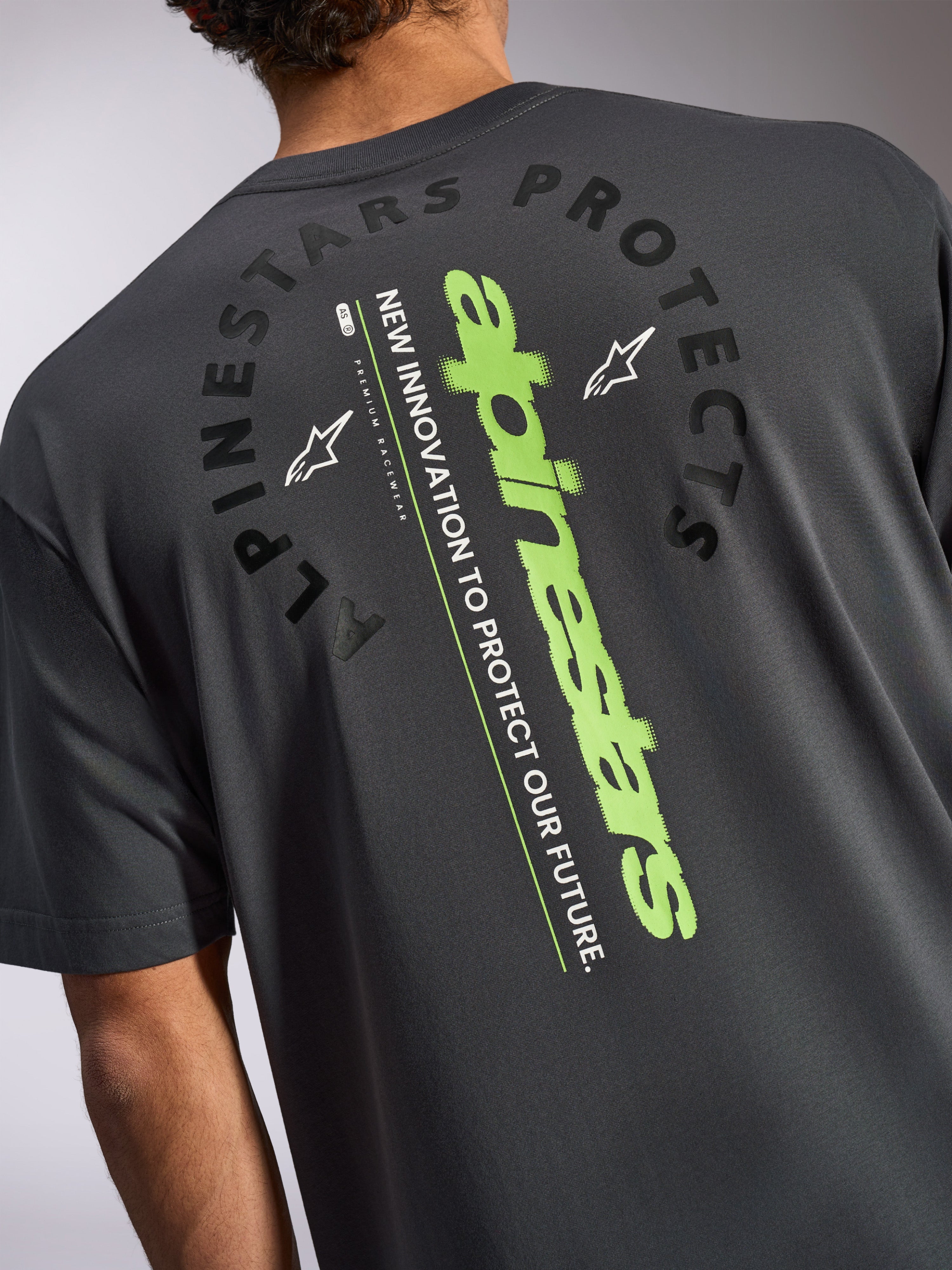 Alpinestars Overhang Oversized CSF Tee, kortærmet T-shirt, koksgrå, set bagfra med et stort lodret limegrønt logo og sort Alpinestars Protects-grafik, afslappet motorsport-inspireret sportstøj