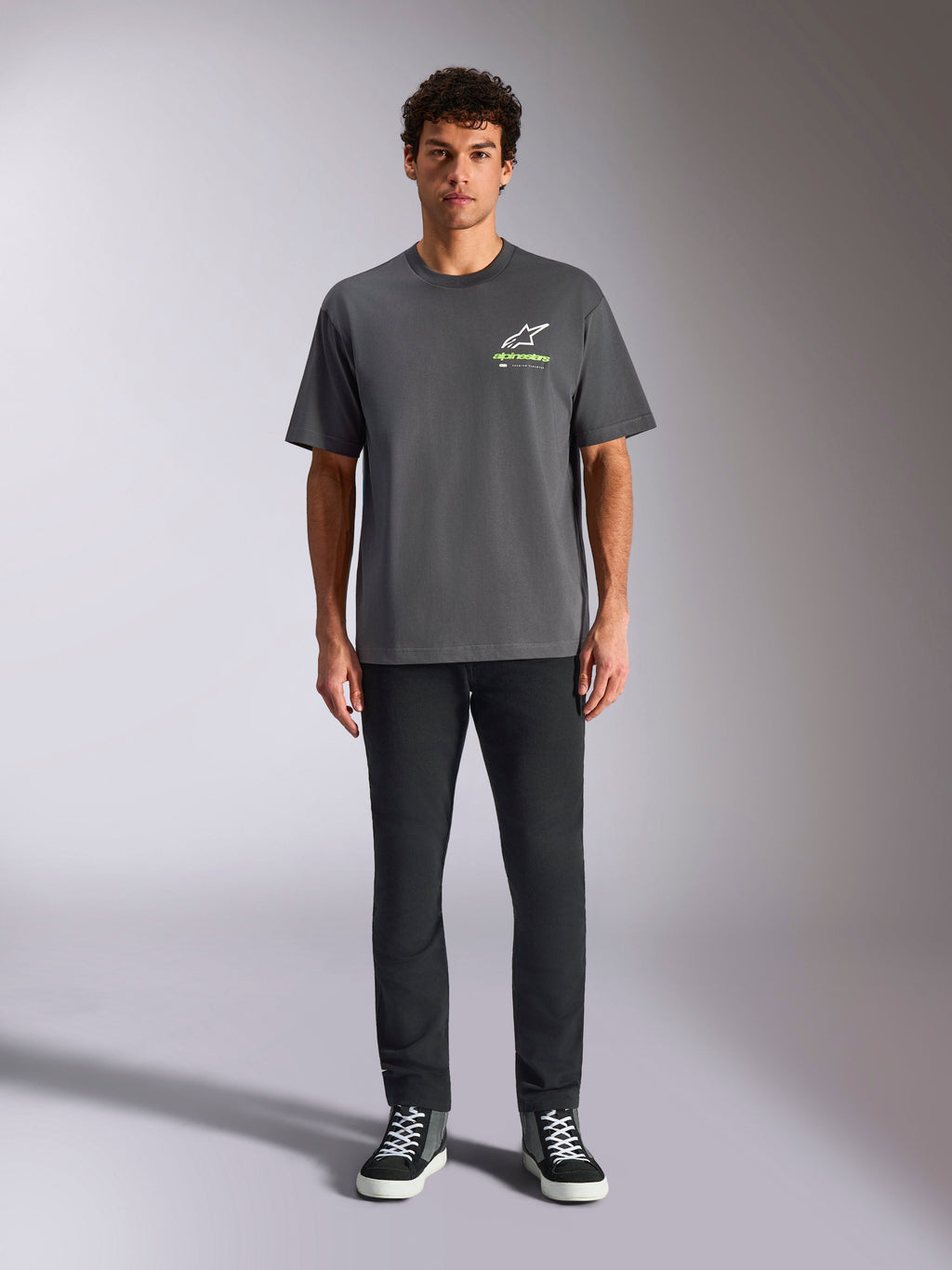 Alpinestars Overhang Oversized CSF Tee, kortærmet T-shirt, koksgrå, med et hvidt og limegrønt Alpinestars-logo på brystet, båret af en model med sorte bukser og sneakers, afslappet casual streetwear