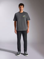 Alpinestars Overhang Oversized CSF Tee, kortærmet T-shirt, koksgrå, med et hvidt og limegrønt Alpinestars-logo på brystet, båret af en model med sorte bukser og sneakers, afslappet casual streetwear