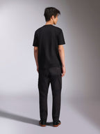 Alpinestars Noka CSF Tee, kortærmet t-shirt, sort, model set bagfra iført t-shirt med sorte bukser og sneakers, afslappet motorsport-streetwear-stil