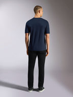 Alpinestars Noka CSF Tee, kortærmet t-shirt, marineblå, set bagfra af en mand iført t-shirten kombineret med sorte bukser og sneakers, afslappet motorsport streetwear