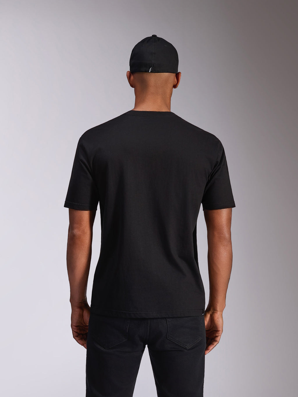Alpinestars Ellipsoid CSF Tee, kortærmet t-shirt, sort, set bagfra på model, båret med en sort kasket og mørke bukser, afslappet motorsport-inspireret streetwear
