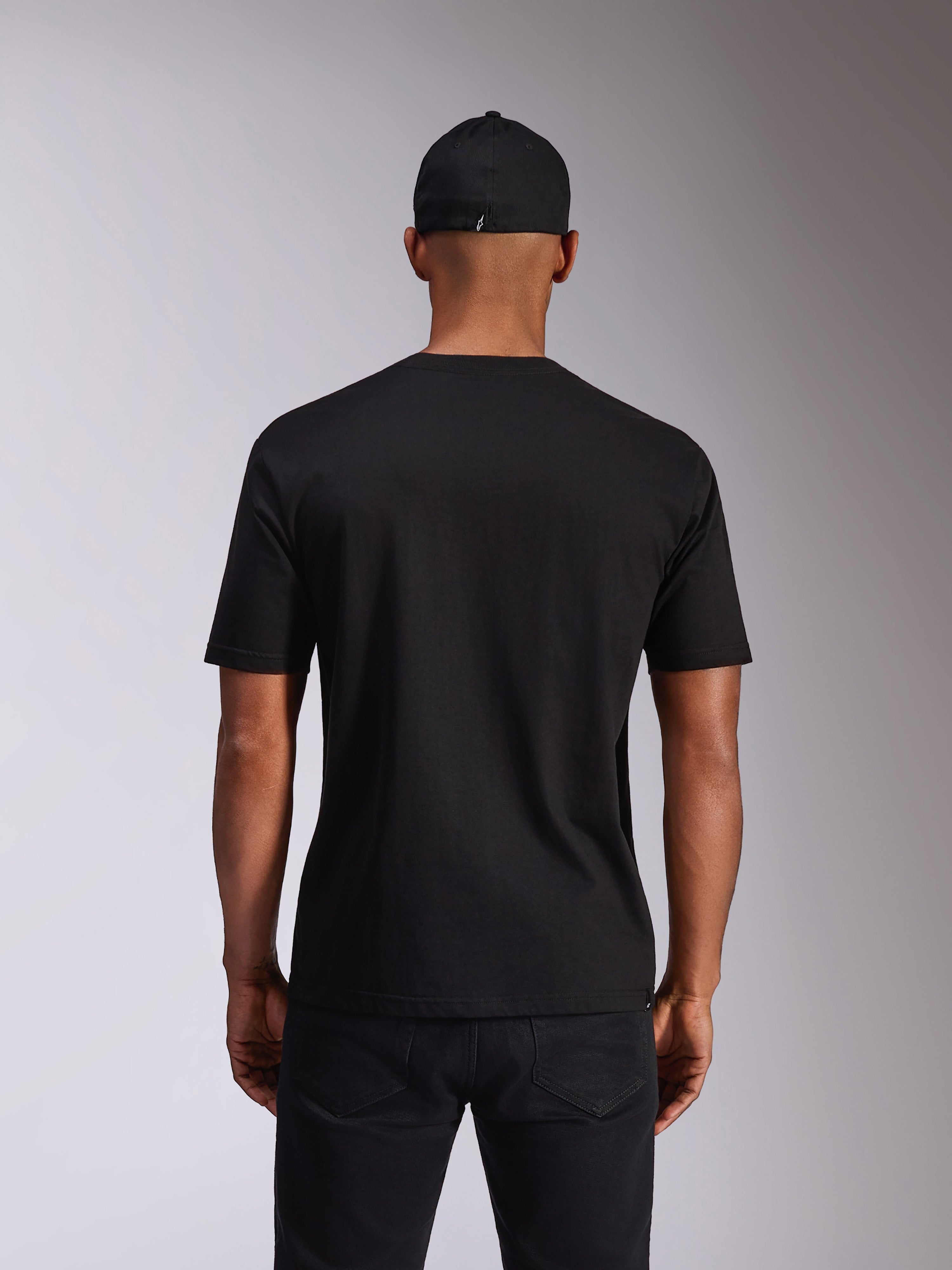 Alpinestars Ellipsoid CSF Tee, kortærmet t-shirt, sort, set bagfra på model, båret med en sort kasket og mørke bukser, afslappet motorsport-inspireret streetwear