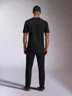 Alpinestars Ellipsoid CSF Tee, kortærmet T-shirt, sort, set bagfra på model med sort kasket og bukser, afslappet motorsport-inspireret streetwear