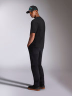 Alpinestars Ellipsoid CSF Tee, kortærmet T-shirt, sort, set bagfra på model iført sorte bukser og en sort Alpinestars kasket, afslappet motorsport-livsstilsoutfit