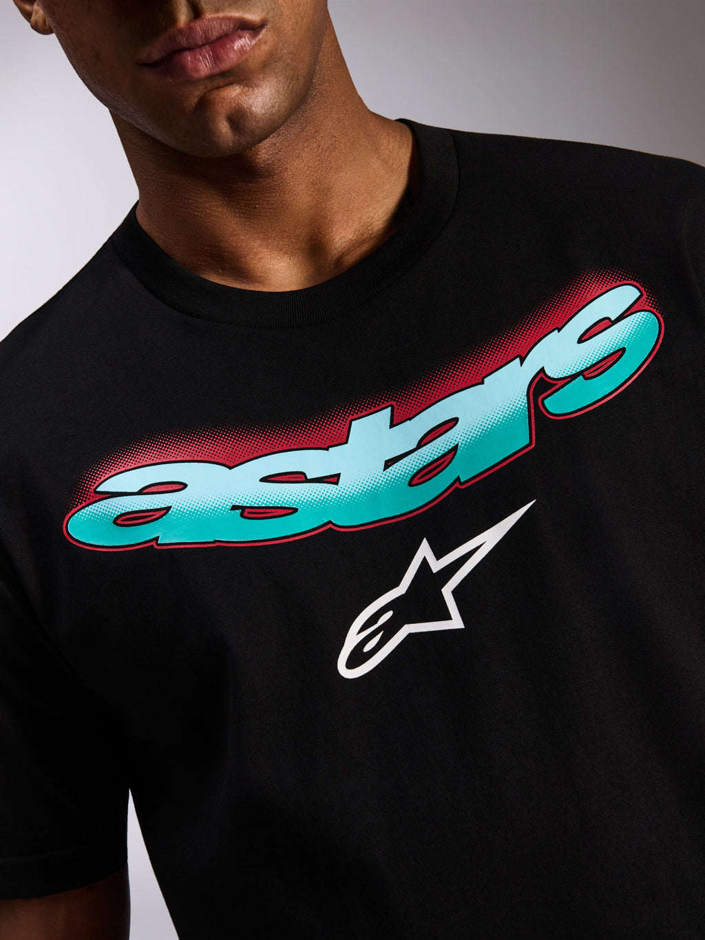 Alpinestars Ellipsoid CSF Tee, kortærmet T-shirt, sort, nærbillede af grafik på fronten med turkis og blå farveovergang i Astars-teksten, rød halvtone-skygge og hvidt stjernelogo, casual motorsport streetwear