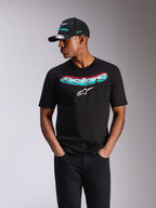 Alpinestars Ellipsoid CSF Tee, kortærmet t-shirt, sort, blågrøn og lyserød farveovergang på Astars-tekst og hvidt logo, bæres af en model med matchende Alpinestars kasket og sorte jeans, afslappet motorsport-streetwear