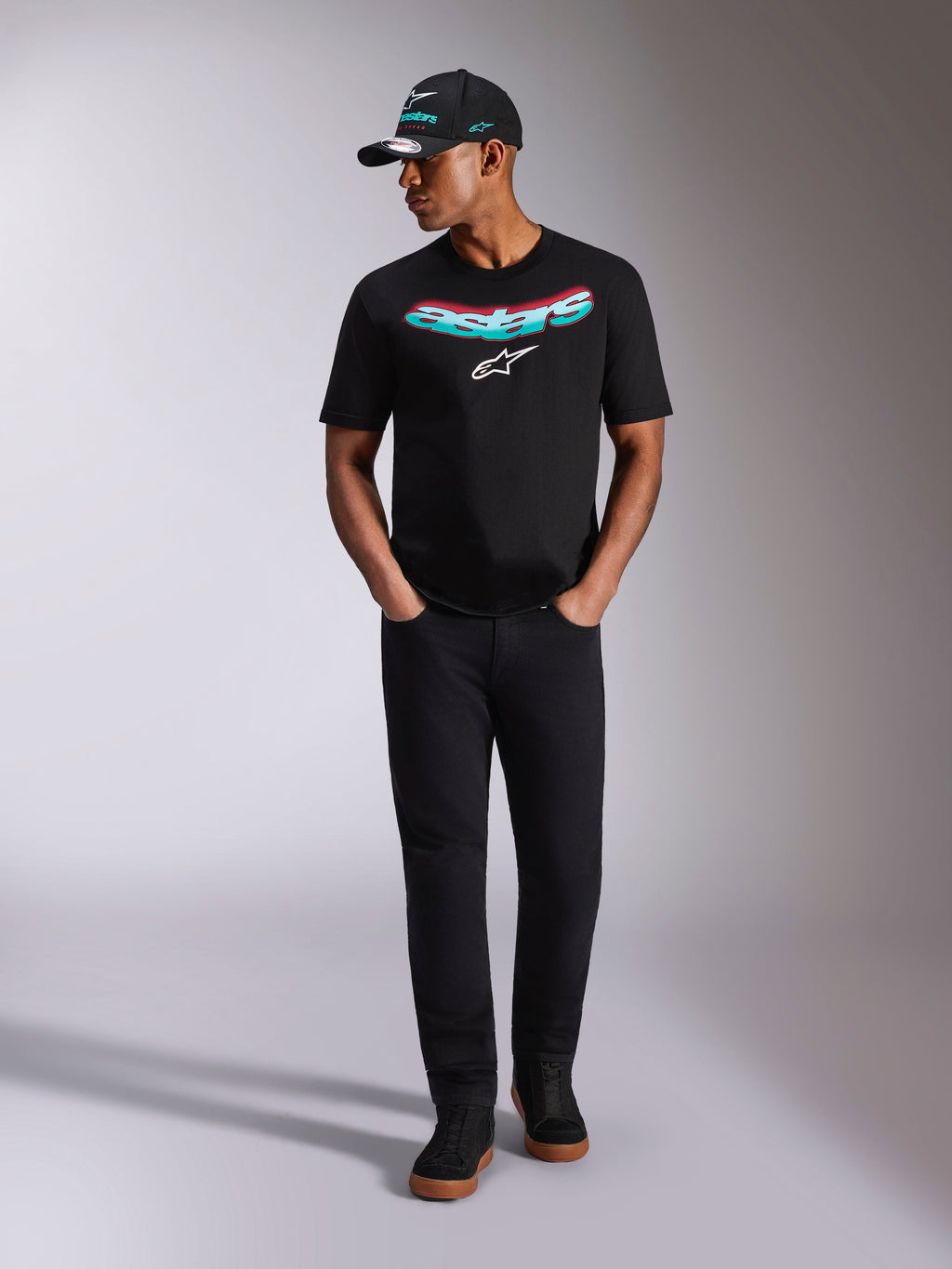 Alpinestars Ellipsoid CSF Tee, kortærmet T-shirt, sort, buet Astars-tekst med blågrøn og lyserød farveovergang og hvidt logo, bæres af model med matchende sort kasket og bukser, afslappet motorsport-livsstilstøj