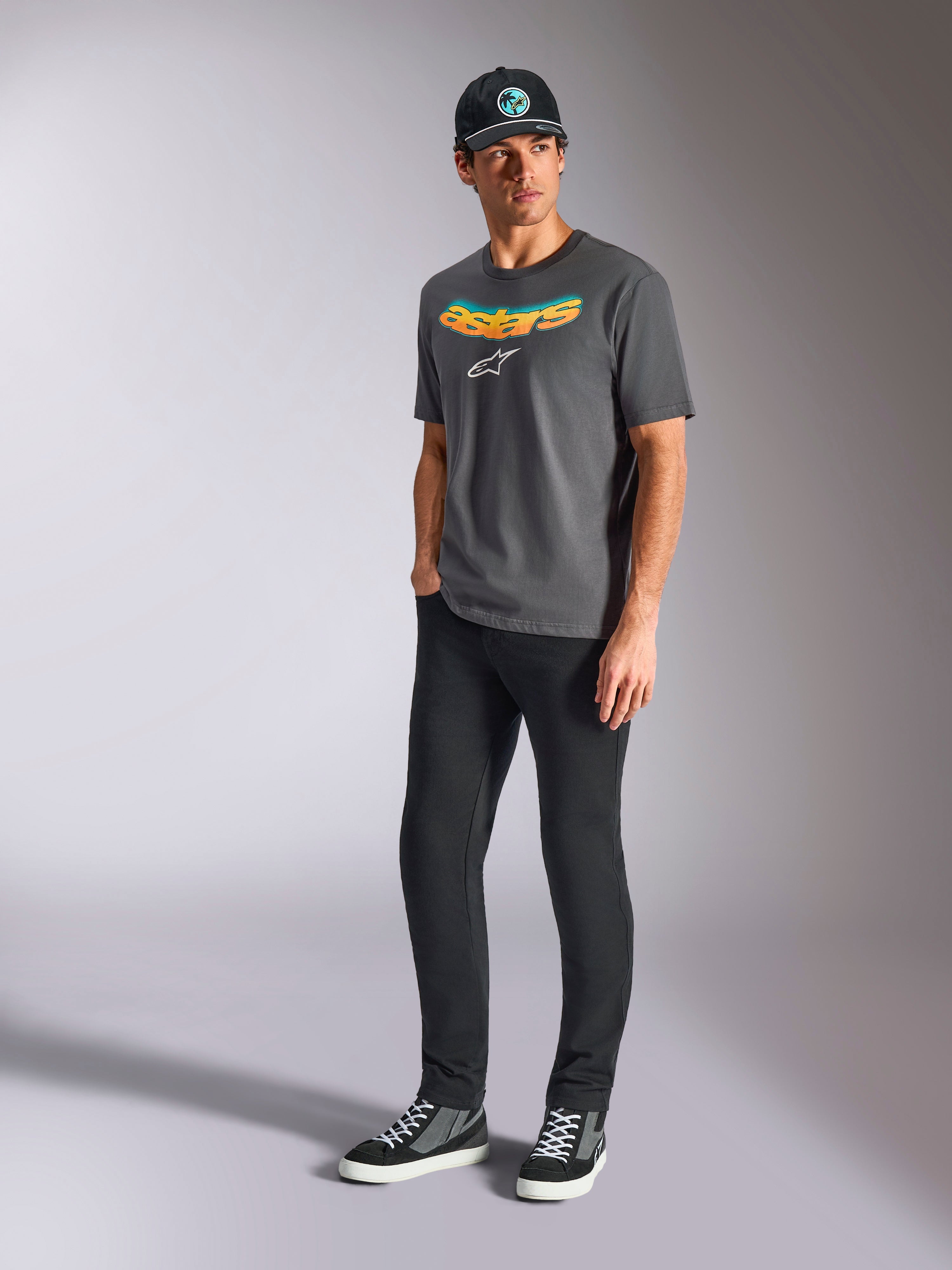 Alpinestars Ellipsoid CSF Tee, Short Sleeve T-Shirt, Charcoal Gray, featuring curved astars wordmark with color gradient and white logo, worn by model with black pants and cap, casual motorsport streetwear