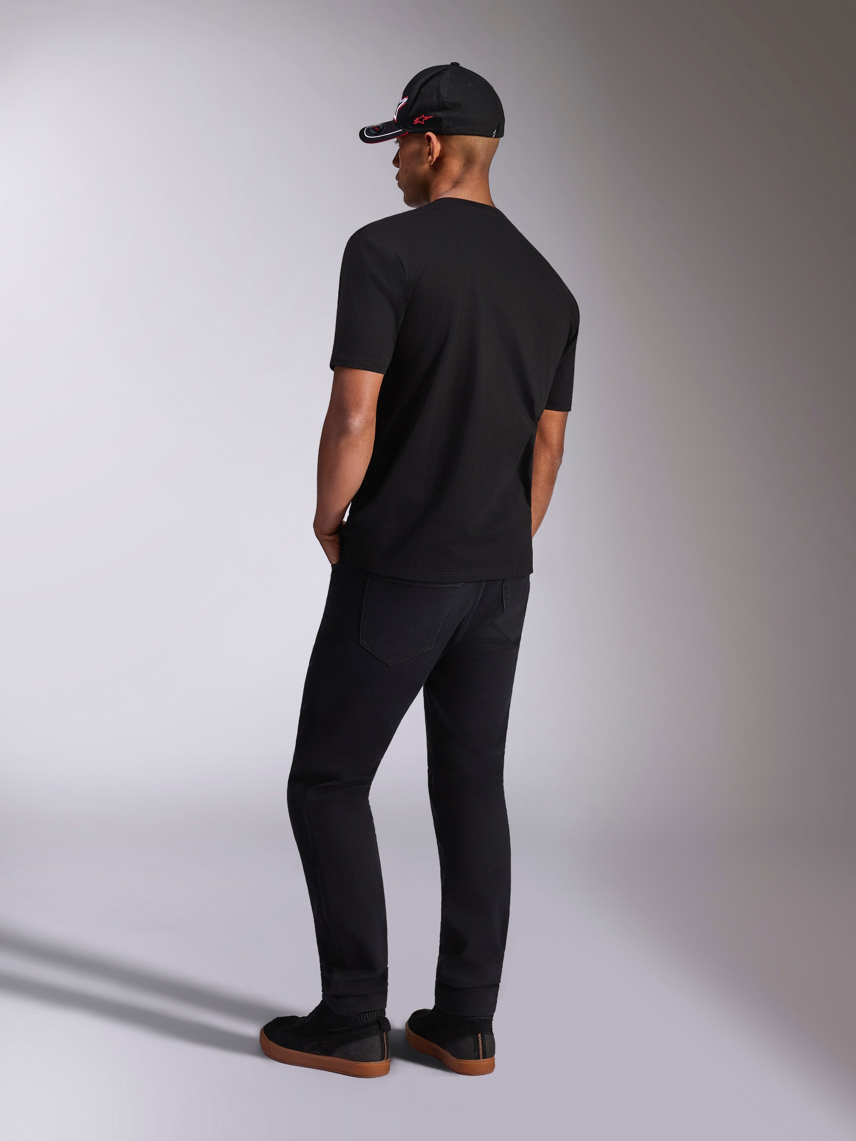 Alpinestars Plate CSF Tee, Short Sleeve T-Shirt, Black, back view on model wearing black pants and a baseball cap, casual motorsport streetwear