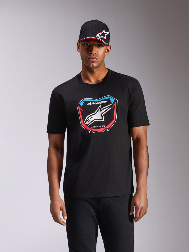 Alpinestars Plate CSF Tee, kortærmet T-shirt, sort, med MX-pladegrafik på fronten med hvidt logo og røde og blå detaljer, båret af model med matchende sort kasket, afslappet motorsport-streetwear