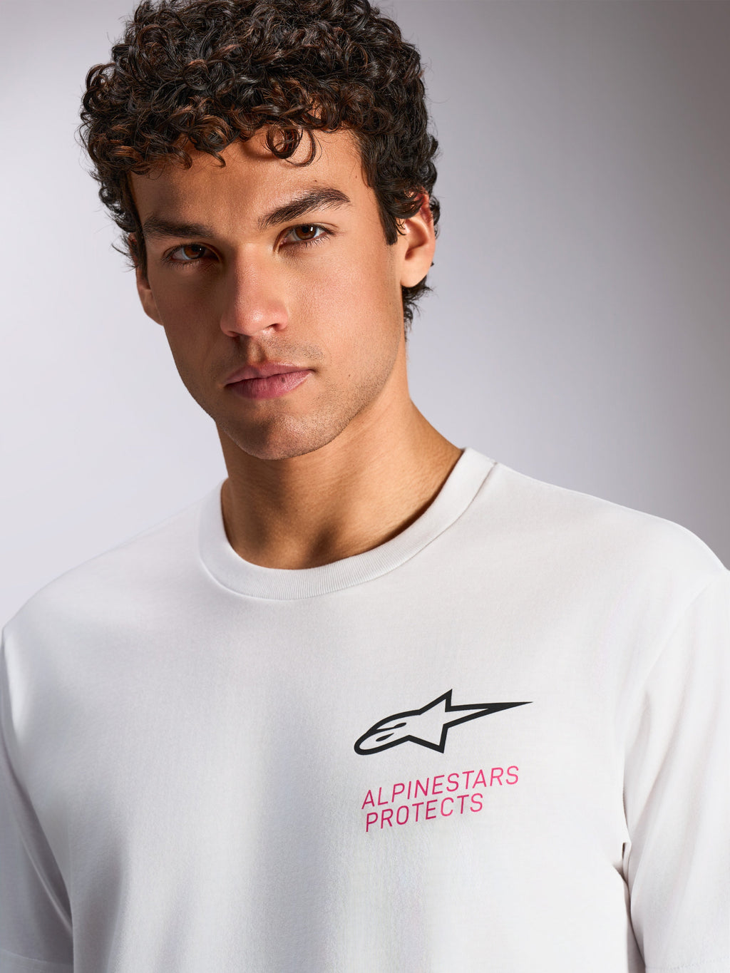 Alpinestars Pop Helmet CSF Tee, kortærmet t-shirt, hvid, sort Astars-logo og lyserød 'ALPINESTARS PROTECTS'-tekst på brystet, afslappet motorsport streetwear