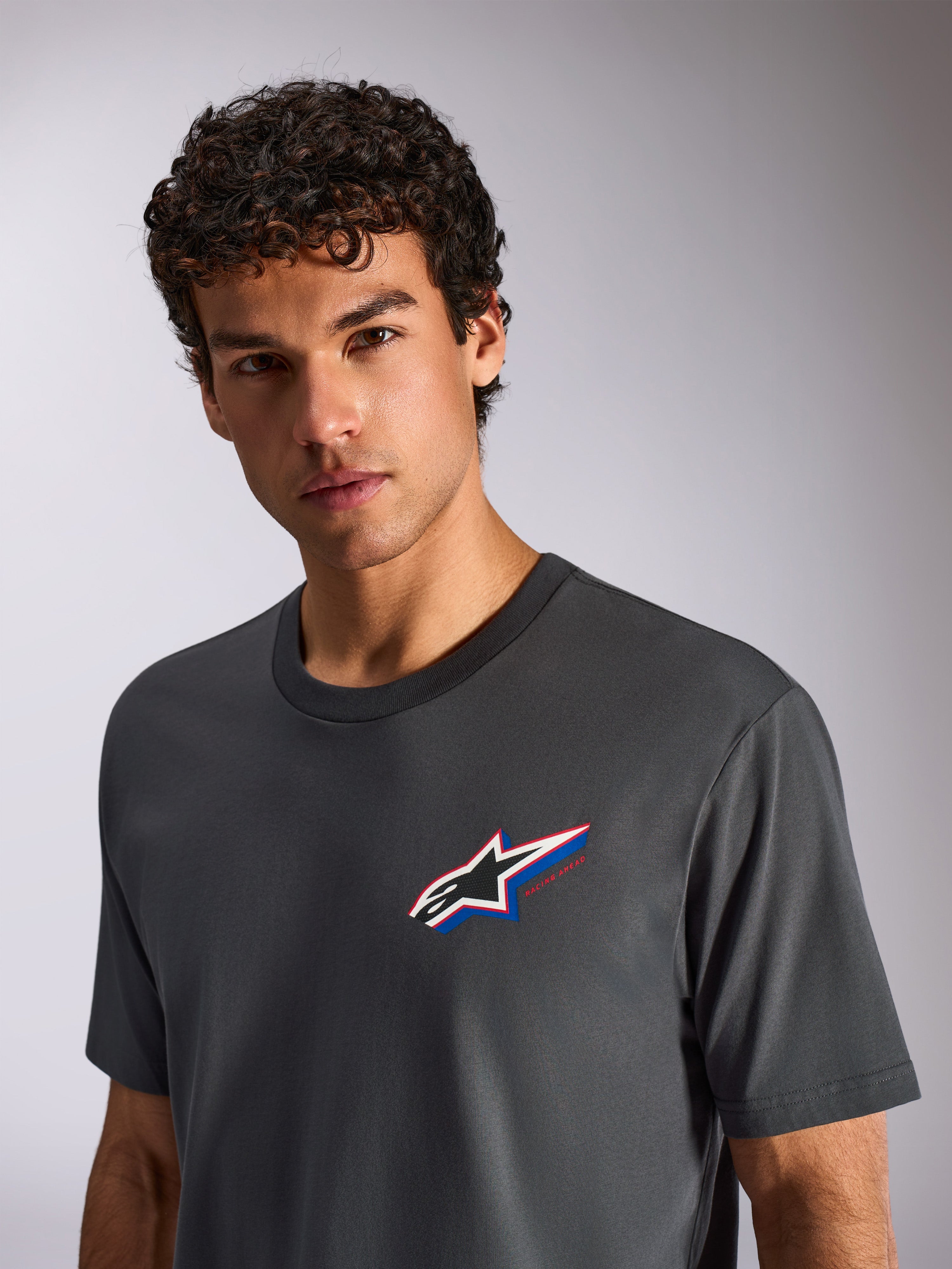 Alpinestars Angler CSF Tee, kortærmet T-shirt, koksgrå, båret af en mandlig model, med et flerfarvet Astars-logo på brystet, afslappet motorsport-streetwear