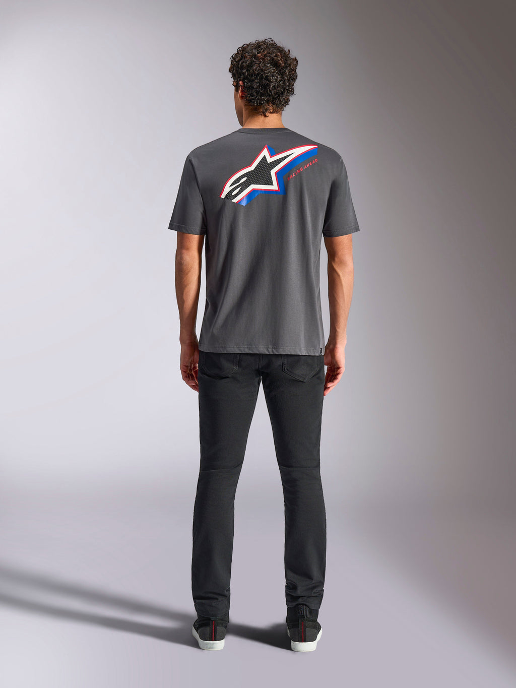 Alpinestars Angler CSF Tee, kortærmet t-shirt, koksgrå, stort flerfarvet Astars-logo på ryggen med røde og blå detaljer, set bagfra på model, afslappet motorsport-streetwear