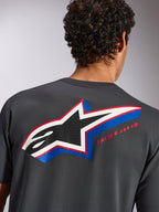 Alpinestars Angler CSF Tee, kortærmet T-shirt, koksgrå, set bagfra på model med et stort flerfarvet Alpinestars-stjernelogo med perforeret fyld og 'RACING AHEAD'-tekst, afslappet motorsport-streetwear