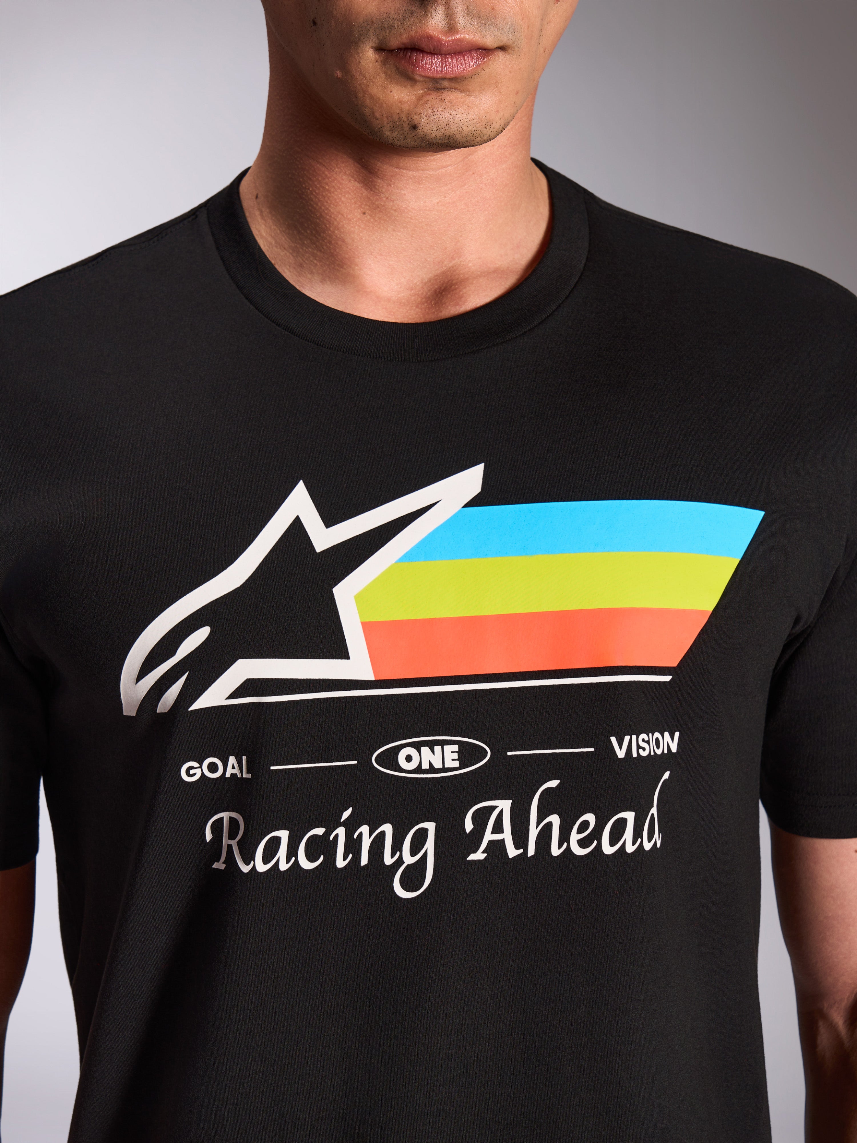 Alpinestars Trifecta CSF Tee, kortærmet T-shirt, sort, nærbillede af grafikken på forsiden med hvidt Astars-logo og trefarvede blå, grønne og orange striber, 'Racing Ahead'-tekst, afslappet motorsport-streetwear
