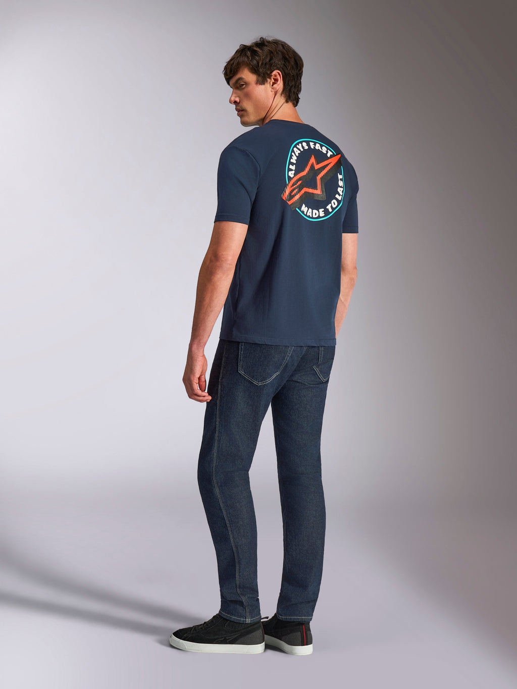 Alpinestars Aorbit CSF Tee, kortærmet T-shirt, marineblå, set bagfra på model med et stort rundt Astars-logo med 'Always Fast Made to Last'-grafik, casual motorsport-inspireret streetwear