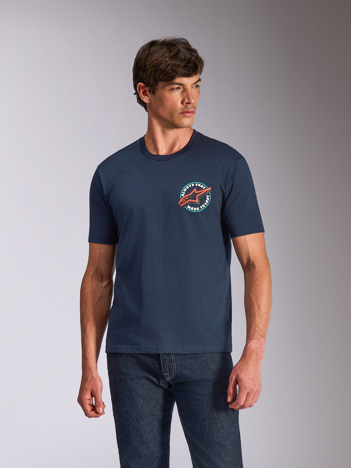 Alpinestars Aorbit CSF Tee, kortærmet T-shirt, mørkeblå, cirkulær brystgrafik med orange Astars-logo og 'Always Fast Made to Last'-tekst, casual motorsport streetwear