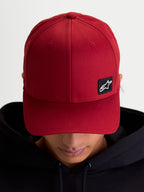 Alpinestars Pivot kasket, mørkerød baseball-kasket i sportswear-stil, unisex, med buet skygge, struktureret krone og et lille sort broderet Astars-logo patch på slidstærkt twill-materiale, vist på model.