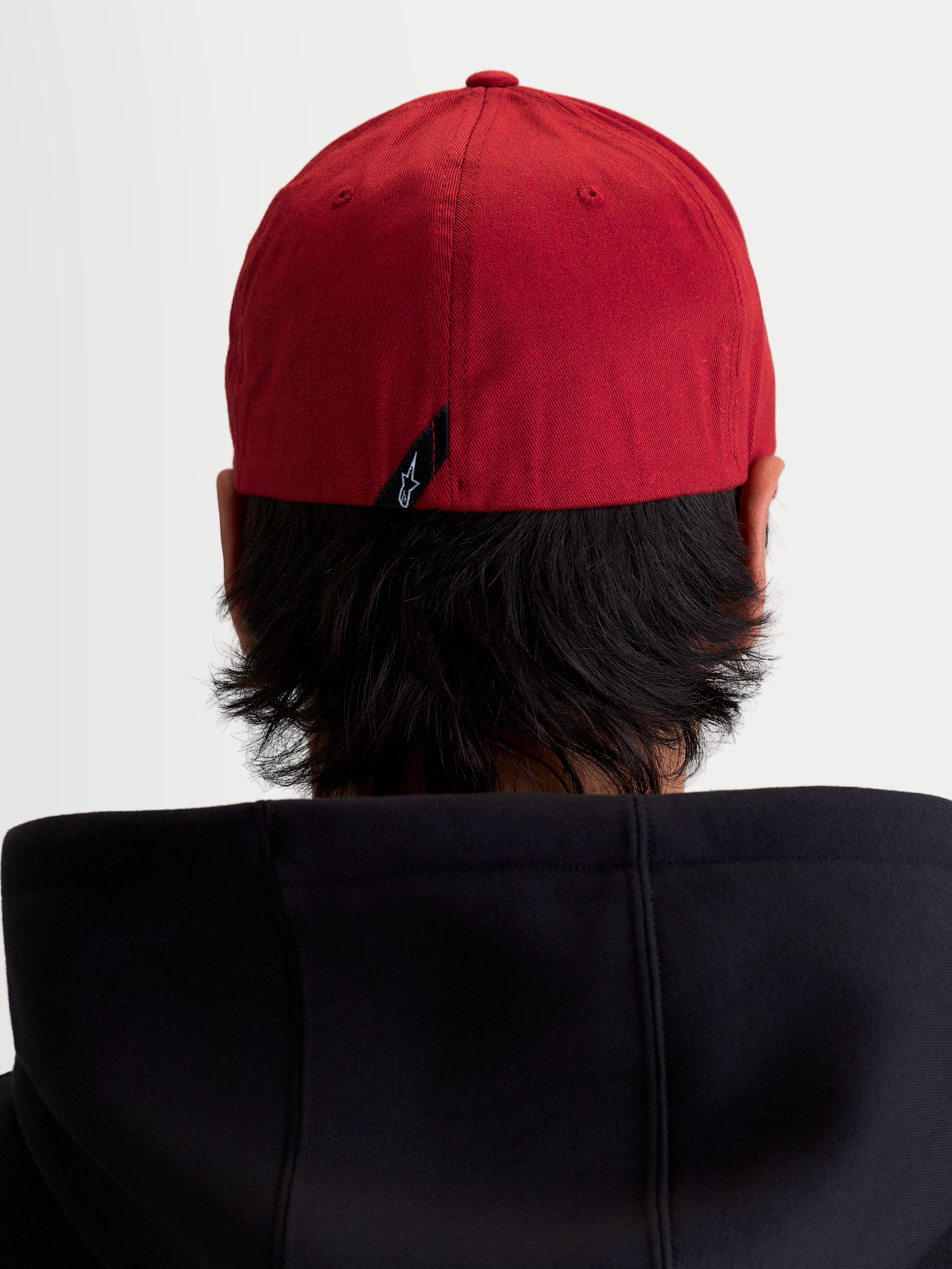 Alpinestars Pivot kasket, mørkerød sportswear baseballkasket, set bagfra på model som viser kaskettens flex back-konstruktion og lille Astars-logolabel bagpå.