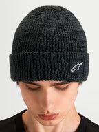 Alpinestars Unload Rib Cuff Beanie, sportswear knit winter hat, charcoal melange gray, featuring a ribbed cuff and woven Alpinestars logo patch, worn by a model in a close-up product view.