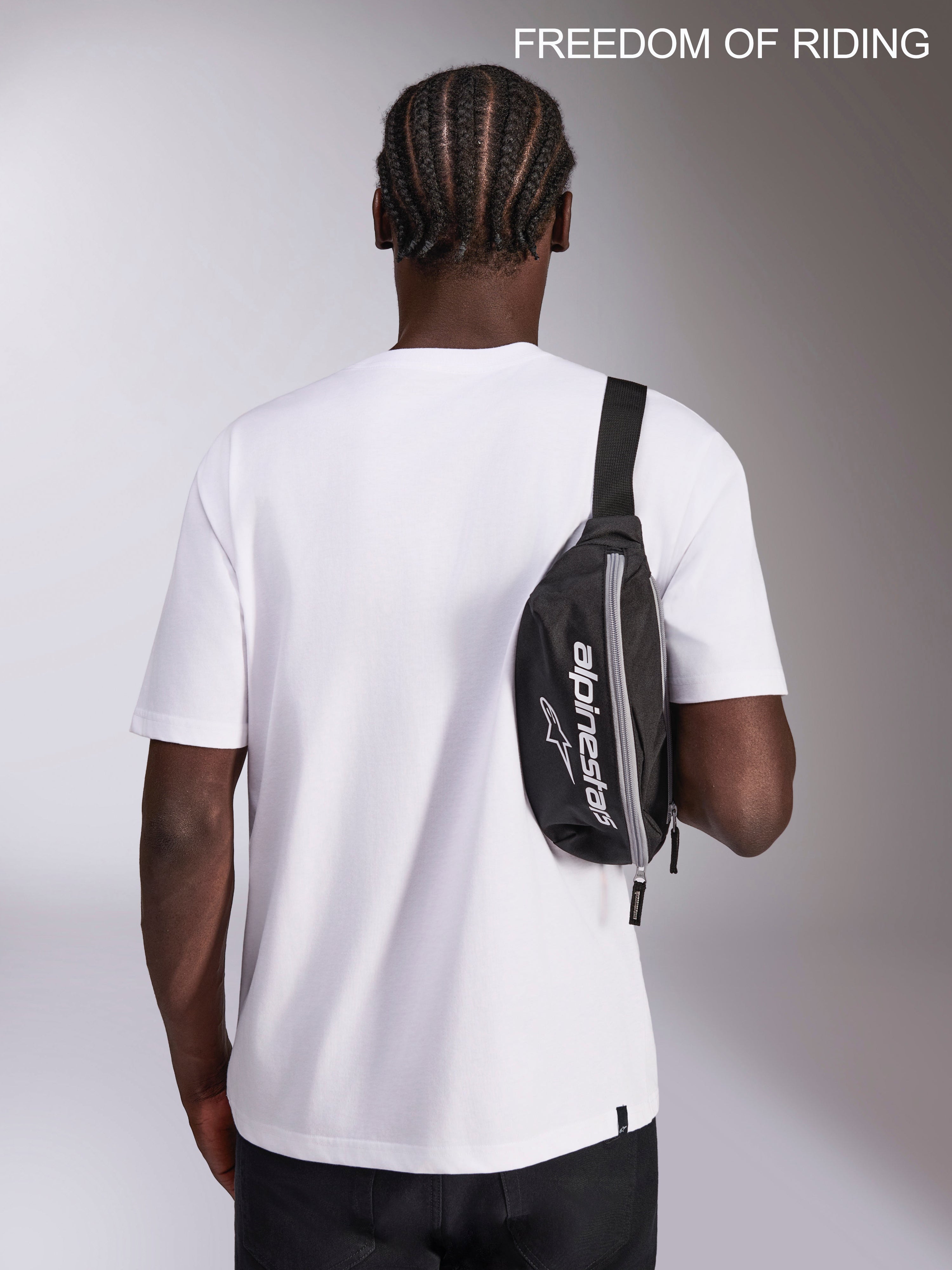 Alpinestars Only Linear hoftebæltetaske, urban sportswear bæltetaske, sort og hvid, 2L kapacitet, 100% polyester med Alpinestars logo-branding, vist båret som en crossbody sling-taske på en model til hverdagsbrug og pendling.