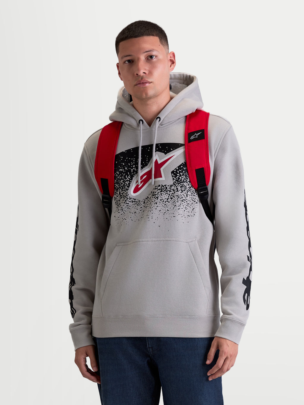 Alpinestars GFX Boss Backpack, 20L Urban Sportswear Daypack, Men's and Women's, Red and Black, Durable 600D Polyester, Front View on Model, featuring adjustable air mesh shoulder straps and raised silicone branding.