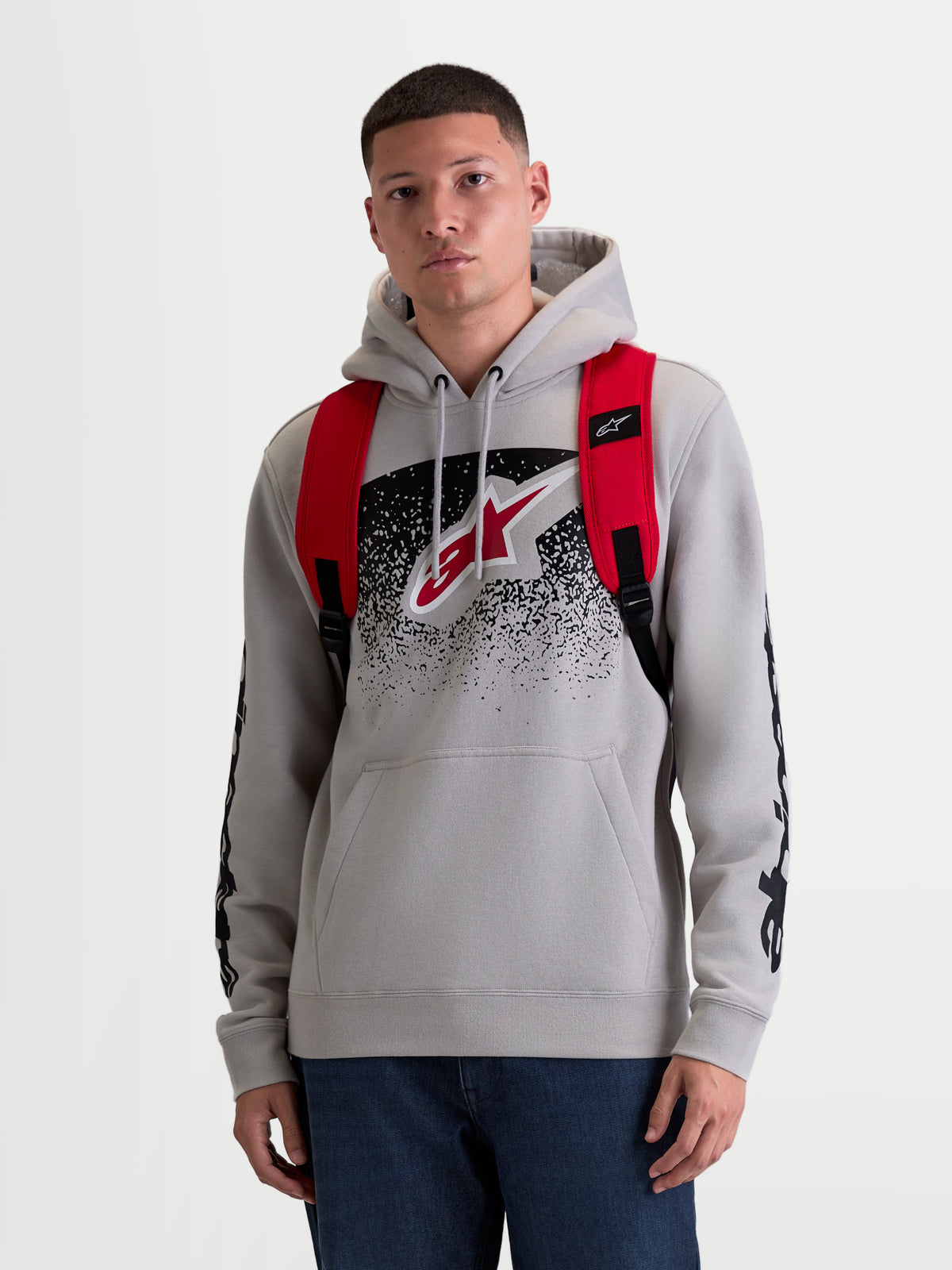 Alpinestars GFX Boss Backpack, 20L Urban Sportswear Daypack, Men's and Women's, Red and Black, Durable 600D Polyester, Front View on Model, featuring adjustable air mesh shoulder straps and raised silicone branding.