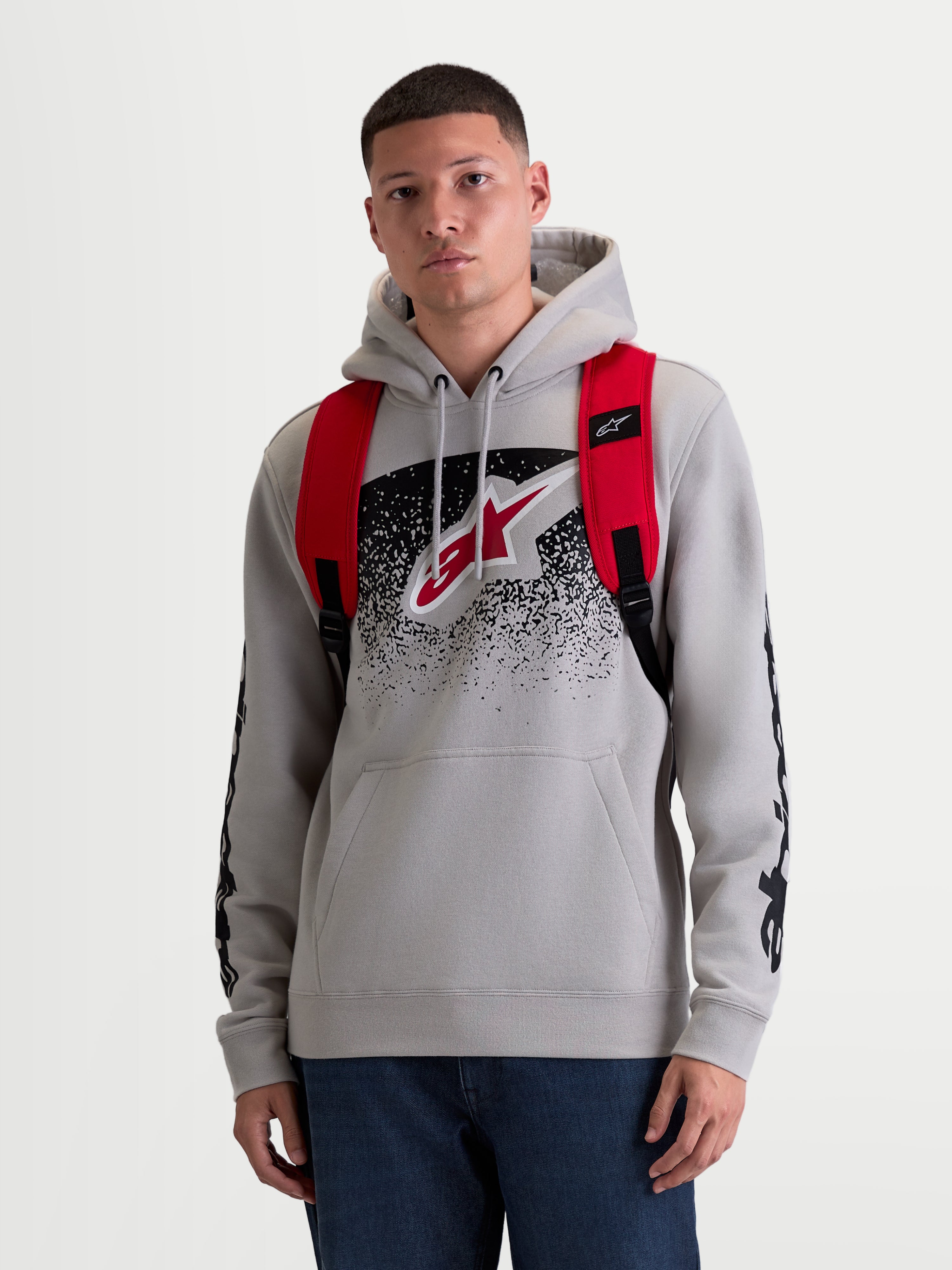 Alpinestars GFX Boss Backpack, 20L Urban Sportswear Daypack, Men's and Women's, Red and Black, Durable 600D Polyester, Front View on Model, featuring adjustable air mesh shoulder straps and raised silicone branding.