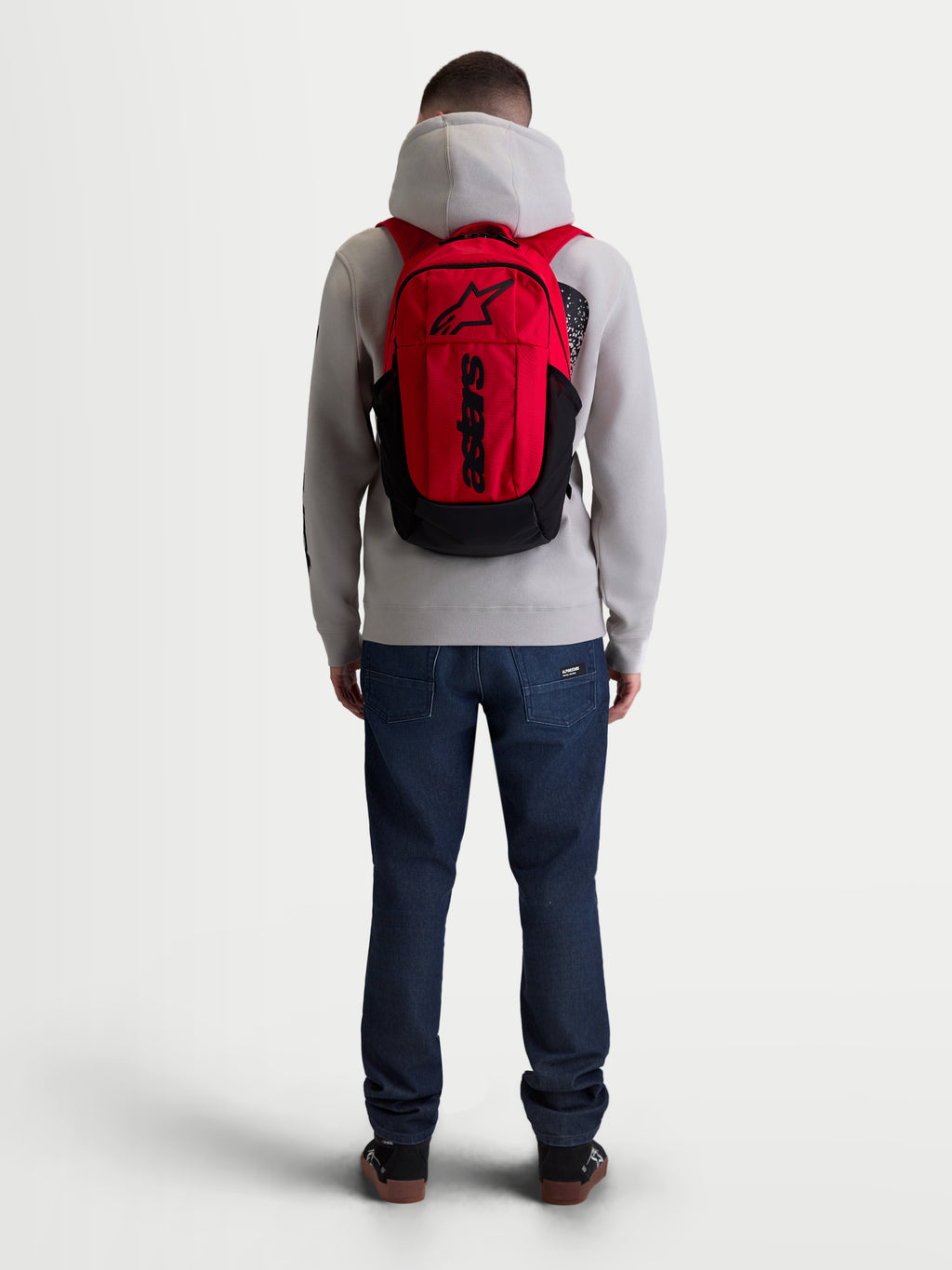 Alpinestars GFX Boss Backpack, 20L Urban Sportswear Daypack, Red and Black, on model back view, featuring durable 600D polyester construction, internal laptop sleeve, and padded air mesh shoulder straps with raised silicone branding.