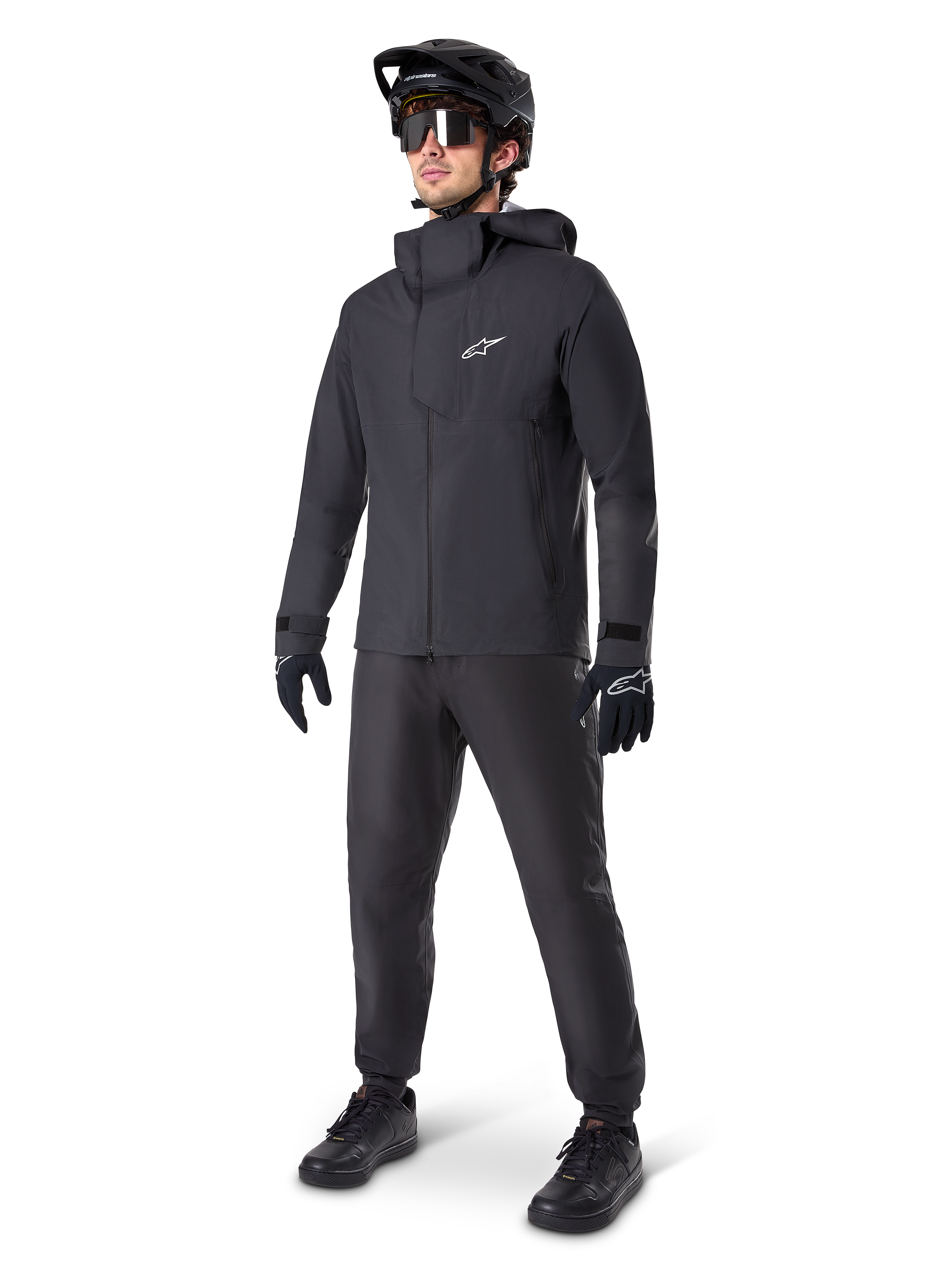 Alpinestars A-Dura Elite vandtæt jakke i sort, båret af en mandlig rytter med matchende sorte MTB-bukser, handsker og hjelm. Jakken har et teknisk vandtæt design med et hvidt Astars-logo på brystet og en høj beskyttende krave.