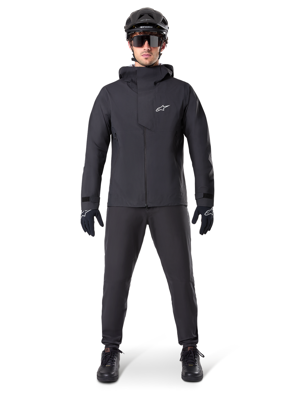 Alpinestars A-Dura Elite vandtæt jakke, sort, båret med matchende cykelbukser og handsker, sort hjelm og solbriller, med et hvidt Astars-logo på brystet, højtydende teknisk design til mountainbiking