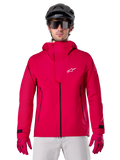 Alpinestars A-Dura Elite vandtæt jakke, MTB-regnjakke, Red Fluo, høj krave med hvidt Alpinestars logo, sorte lynlåsdetaljer, bæres med matchende handsker og sort cykelhjelm, teknisk vandtæt cykeludstyr
