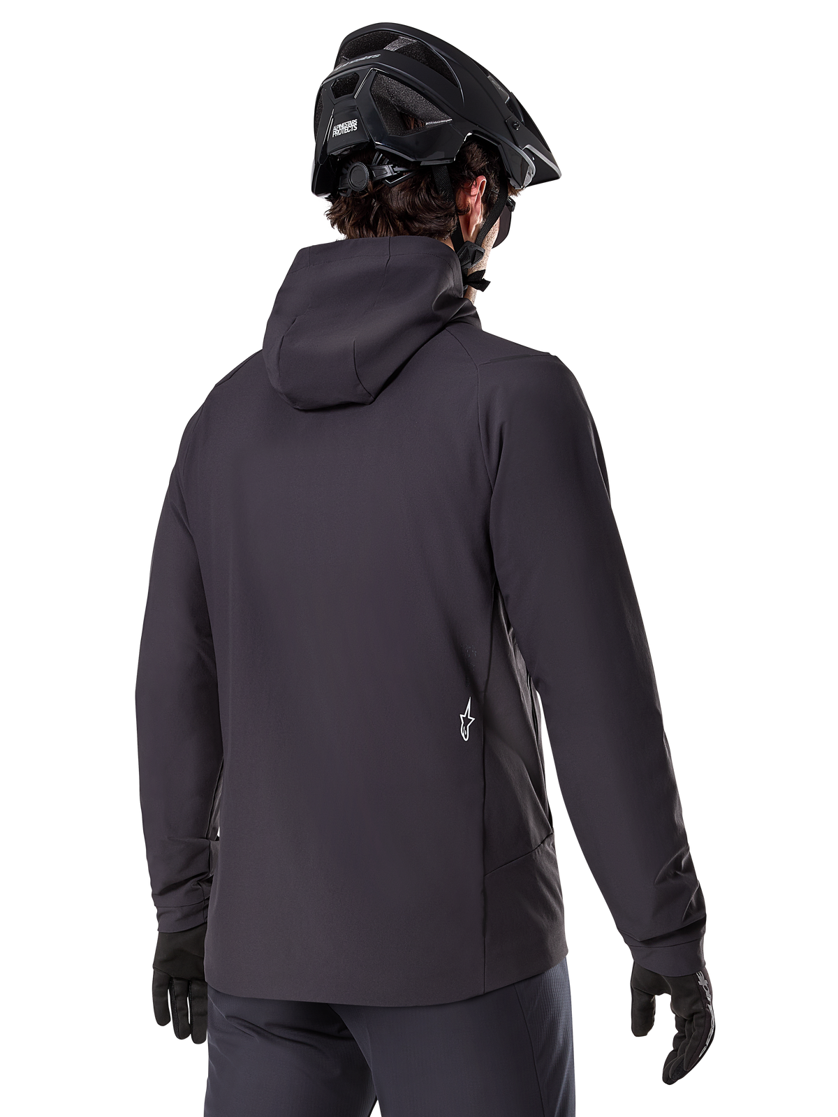 Alpinestars A-Dura Thermal Jacket, sort, set bagfra, båret med en sort mountainbikehjelm og handsker, har et lille hvidt Astars-logo nederst på ryggen, letvægts isoleret cykeljakke