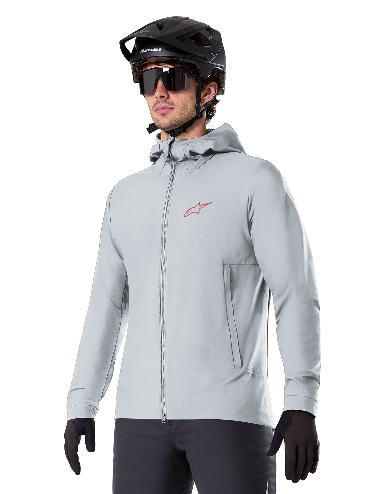 Alpinestars A-Dura Thermal Jacket, lysegrå isoleret cykeljakke, design med hætte og et lille rødt logo, båret med sort hjelm og handsker, teknisk mountainbike-beklædning til kørsel i koldt vejr